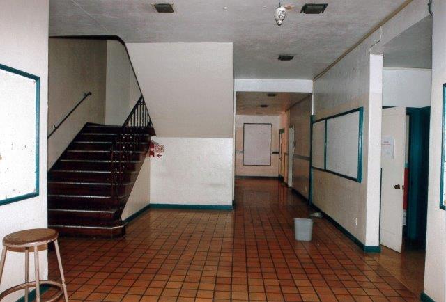 Before: Interior view of school entrance foyer facing east with stairs to the left and corridor straight ahead.